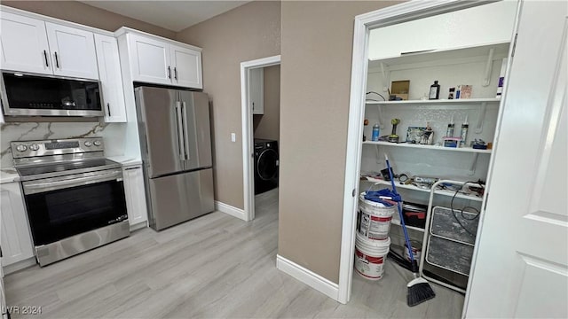 kitchen featuring washer / dryer, white cabinetry, light hardwood / wood-style flooring, and appliances with stainless steel finishes