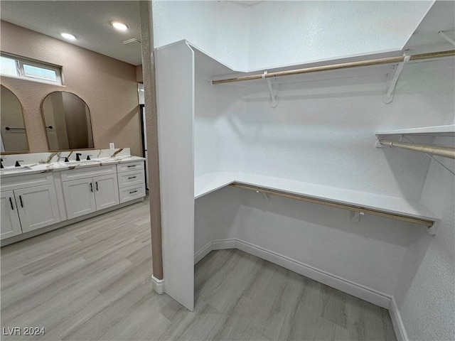 walk in closet featuring light hardwood / wood-style flooring and sink