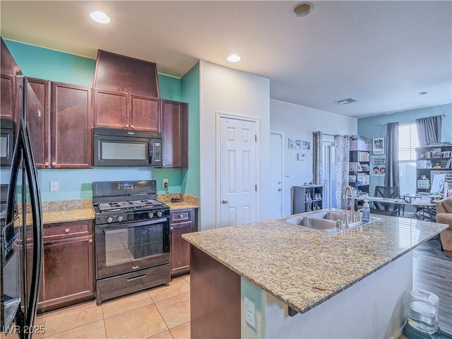 kitchen featuring black appliances, a center island with sink, sink, light stone countertops, and light tile patterned flooring