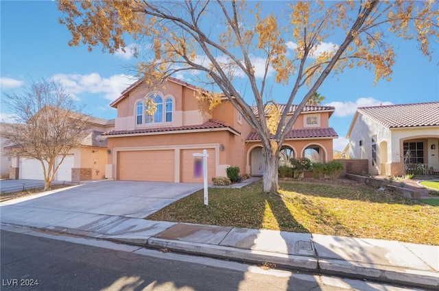 mediterranean / spanish home featuring a garage and a front lawn