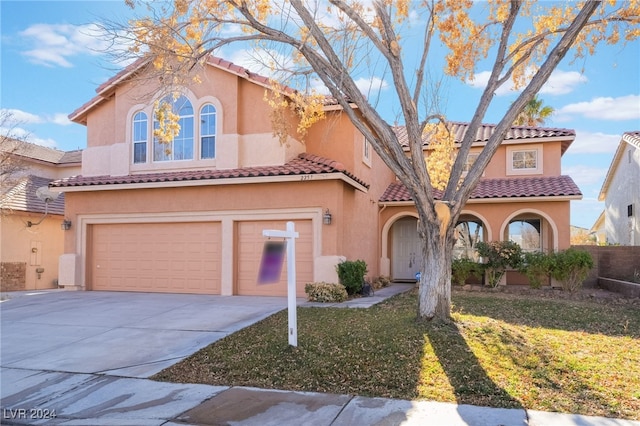 mediterranean / spanish-style home featuring a front lawn and a garage