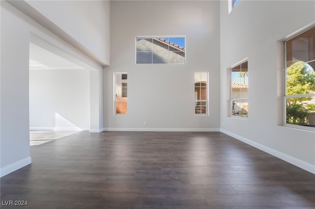 unfurnished room featuring a towering ceiling and dark hardwood / wood-style floors