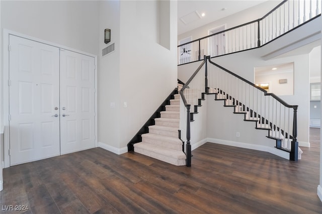 foyer entrance featuring a towering ceiling and dark hardwood / wood-style floors