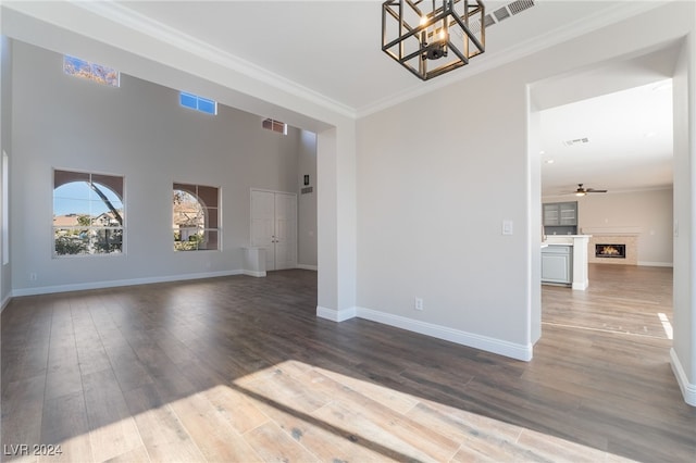 spare room with ornamental molding, ceiling fan with notable chandelier, and wood-type flooring