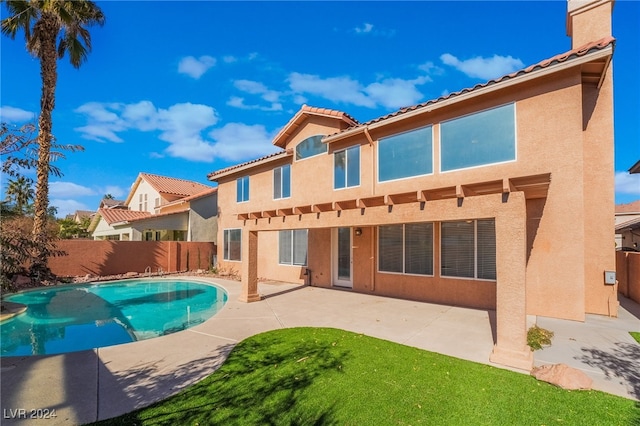 rear view of house featuring a patio and a fenced in pool