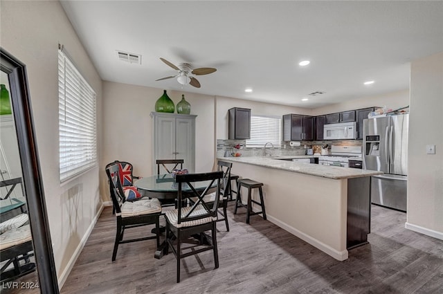 kitchen featuring white appliances, hardwood / wood-style floors, kitchen peninsula, and ceiling fan