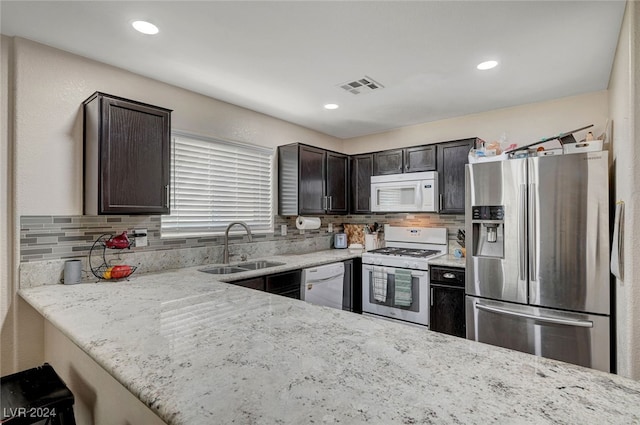 kitchen with white appliances, light stone counters, and tasteful backsplash