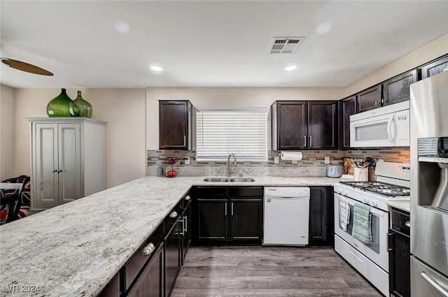 kitchen featuring backsplash, sink, hardwood / wood-style floors, and white appliances