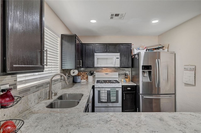 kitchen with gas range oven, decorative backsplash, stainless steel fridge with ice dispenser, and sink