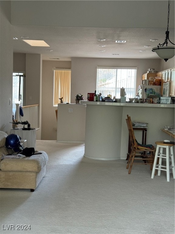 kitchen with a textured ceiling, carpet flooring, kitchen peninsula, hanging light fixtures, and a skylight