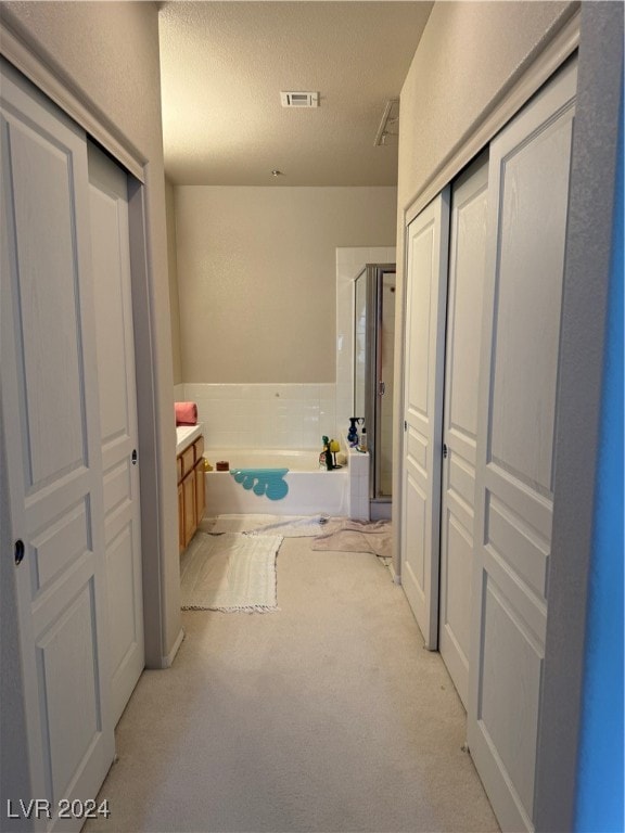 bathroom featuring a textured ceiling, vanity, and separate shower and tub