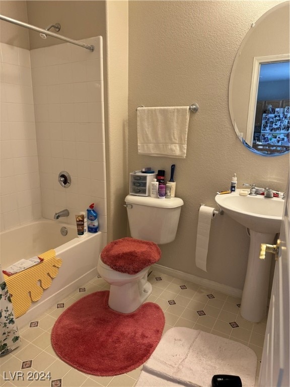 bathroom featuring tile patterned flooring, tiled shower / bath, and toilet