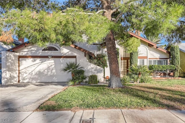 view of front of house with stucco siding, an attached garage, concrete driveway, and a front lawn