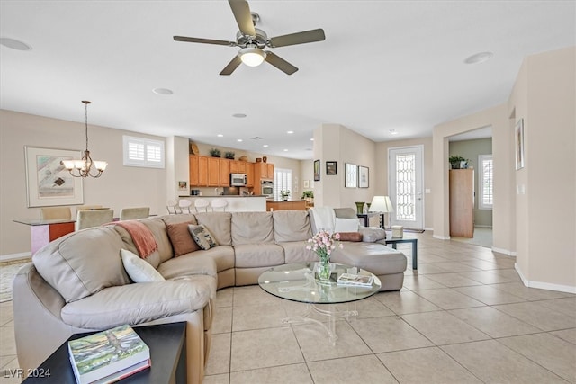 tiled living room with ceiling fan with notable chandelier and a healthy amount of sunlight