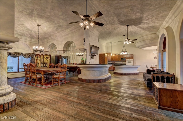 interior space featuring ceiling fan with notable chandelier, dark hardwood / wood-style flooring, and high vaulted ceiling