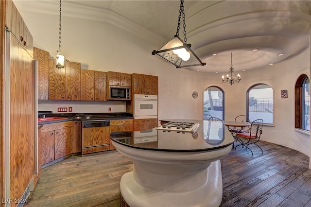 kitchen with white appliances, a chandelier, decorative light fixtures, wood-type flooring, and vaulted ceiling