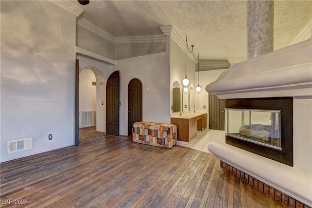 unfurnished living room featuring a high ceiling, hardwood / wood-style floors, and ornamental molding