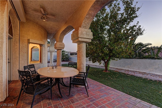 patio terrace at dusk featuring ceiling fan