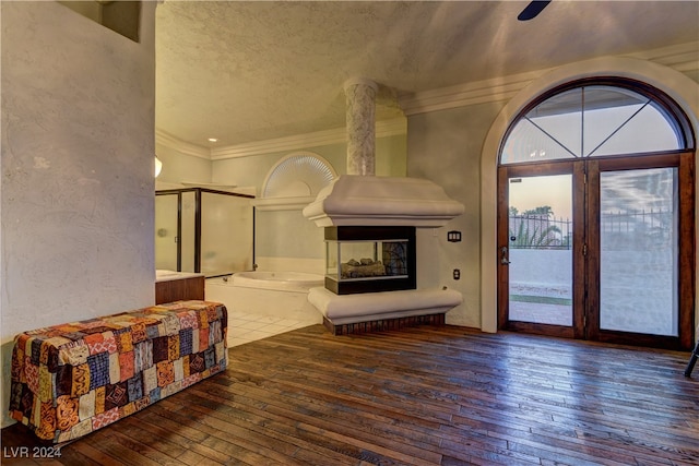 living room with hardwood / wood-style flooring, crown molding, ceiling fan, a multi sided fireplace, and a textured ceiling