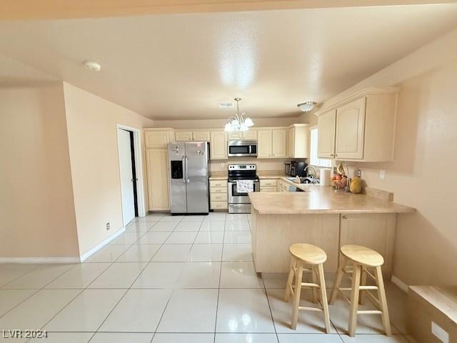 kitchen featuring pendant lighting, sink, appliances with stainless steel finishes, kitchen peninsula, and a breakfast bar area