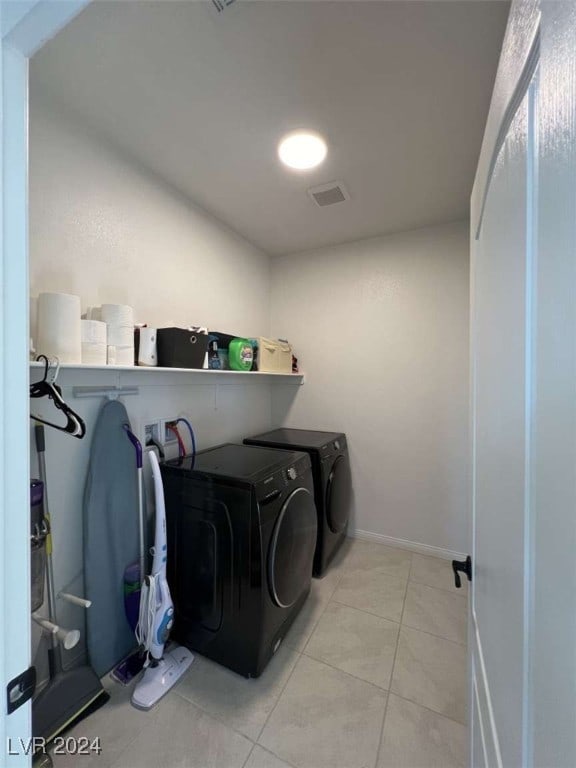 clothes washing area with light tile patterned flooring and independent washer and dryer