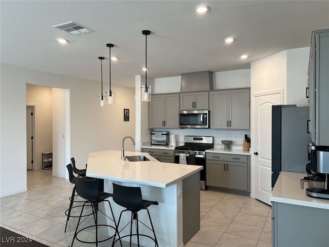 kitchen featuring pendant lighting, sink, stainless steel appliances, a center island with sink, and light tile patterned floors