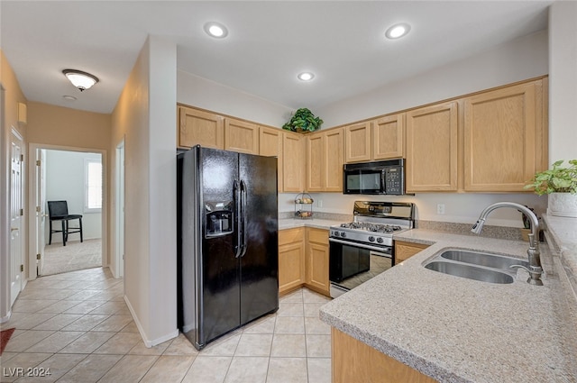 kitchen with black appliances, sink, light tile patterned floors, light stone countertops, and light brown cabinetry