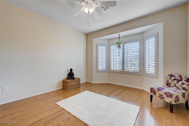 living area featuring ceiling fan with notable chandelier and light wood-type flooring