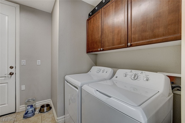 laundry room with cabinets, light tile patterned flooring, and washer and dryer