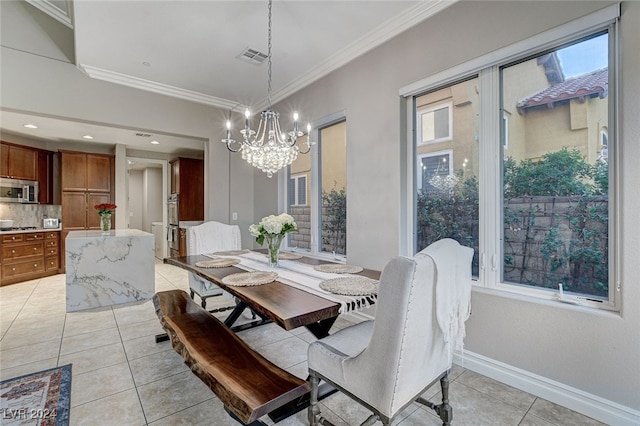 tiled dining area featuring ornamental molding and an inviting chandelier