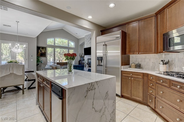 kitchen with lofted ceiling, a center island, decorative backsplash, appliances with stainless steel finishes, and decorative light fixtures