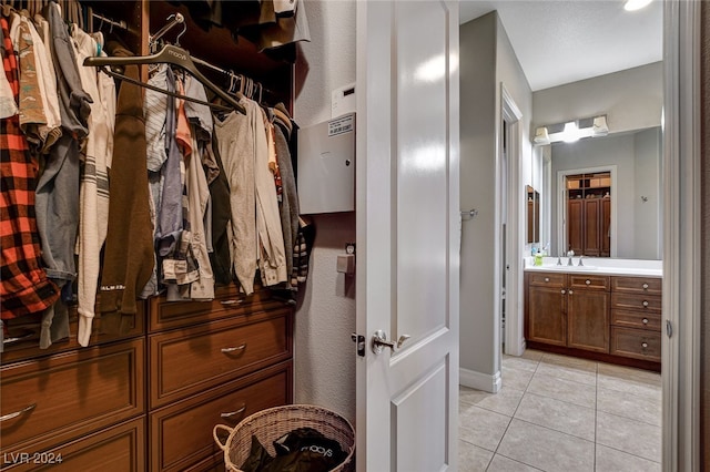 walk in closet with light tile patterned floors and sink