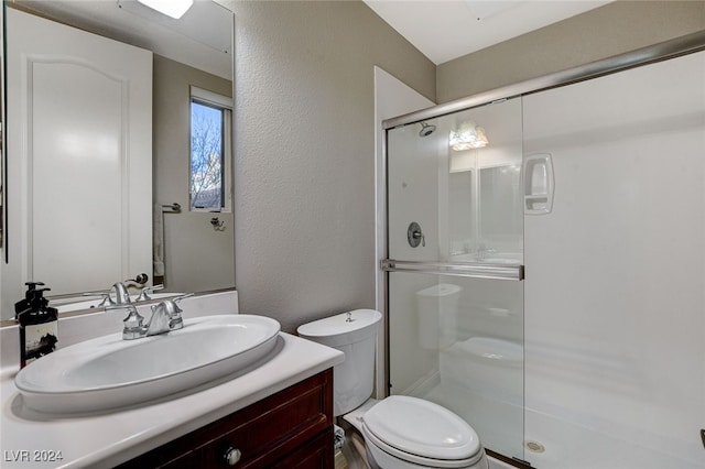 bathroom with toilet, vanity, and a shower with door