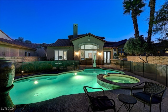 pool at dusk featuring a patio, french doors, and an in ground hot tub