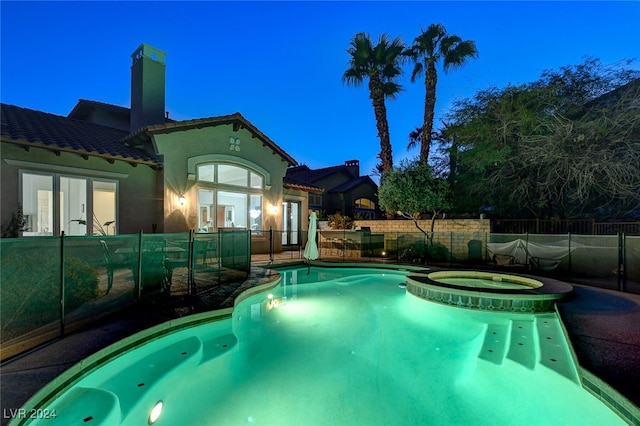 pool at dusk featuring french doors and an in ground hot tub