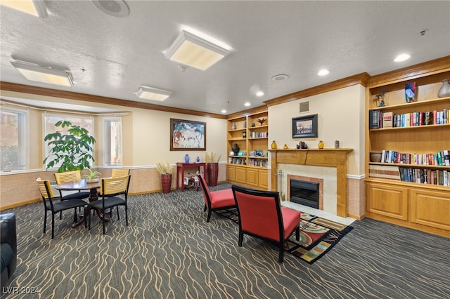 living area featuring dark colored carpet, a tiled fireplace, crown molding, and a textured ceiling