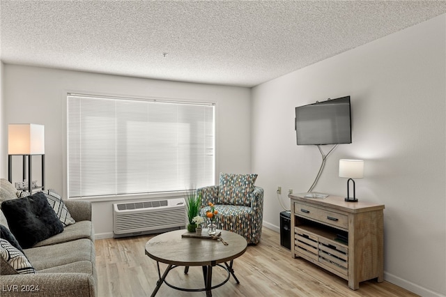 living room featuring a textured ceiling, a wall mounted air conditioner, and light hardwood / wood-style floors