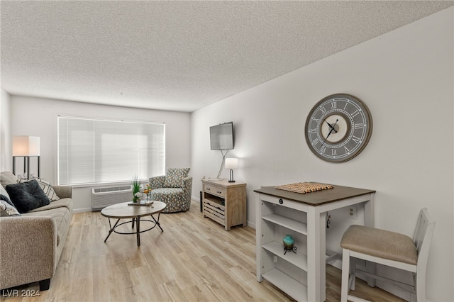 living room featuring a wall unit AC, a textured ceiling, and light hardwood / wood-style flooring