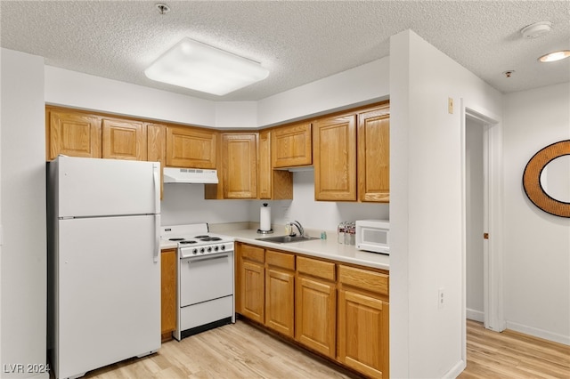 kitchen featuring white appliances, light hardwood / wood-style floors, a textured ceiling, and sink