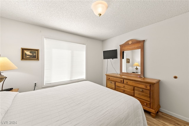 bedroom featuring light hardwood / wood-style floors and a textured ceiling