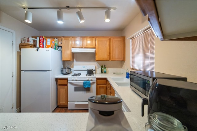 kitchen featuring track lighting, white appliances, sink, and light hardwood / wood-style floors