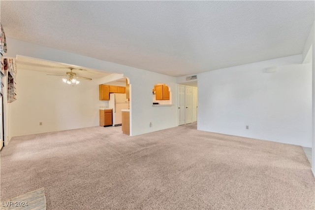 unfurnished living room featuring carpet flooring, ceiling fan, and a textured ceiling