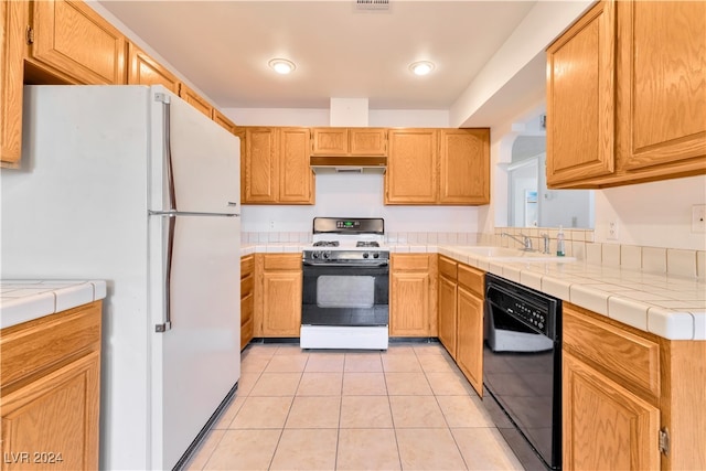 kitchen with light tile patterned floors, white appliances, sink, and tile counters