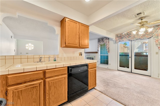 kitchen with tile counters, sink, ceiling fan, black dishwasher, and light colored carpet