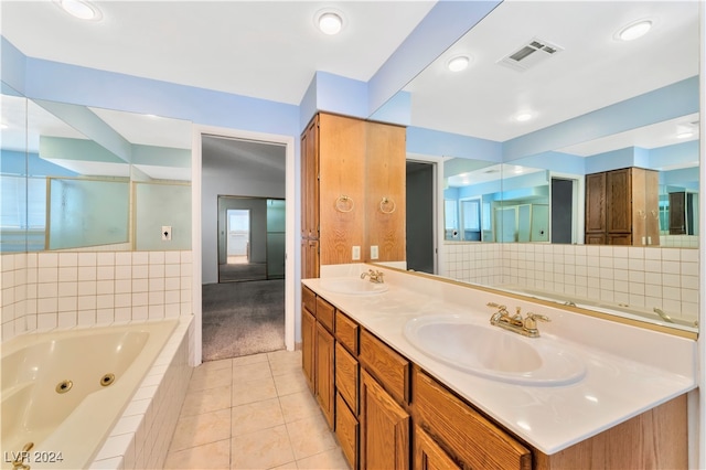 bathroom featuring tile patterned flooring, vanity, and tiled bath