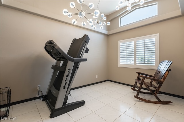 exercise room with a high ceiling, an inviting chandelier, and light tile patterned flooring