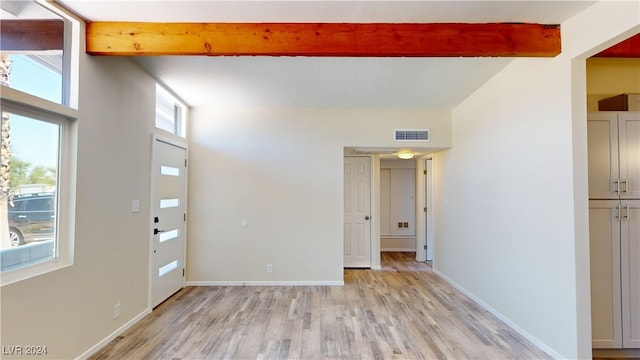 unfurnished room featuring light wood-type flooring and beam ceiling