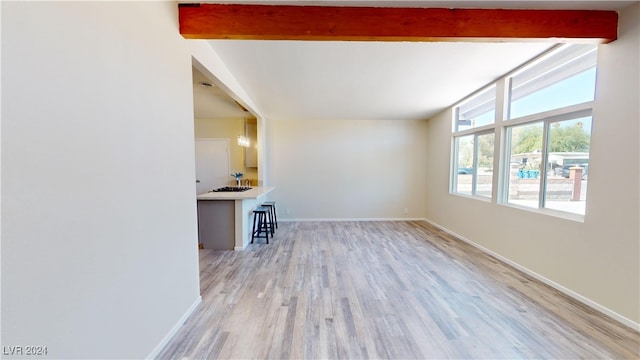 unfurnished living room with beamed ceiling and light wood-type flooring