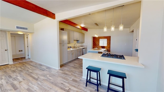 kitchen with gray cabinetry, hanging light fixtures, a breakfast bar, kitchen peninsula, and light wood-type flooring