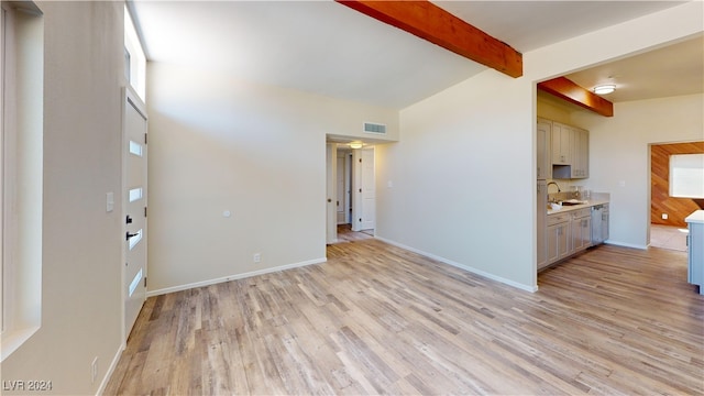 kitchen featuring light hardwood / wood-style flooring, stainless steel dishwasher, sink, and lofted ceiling with beams